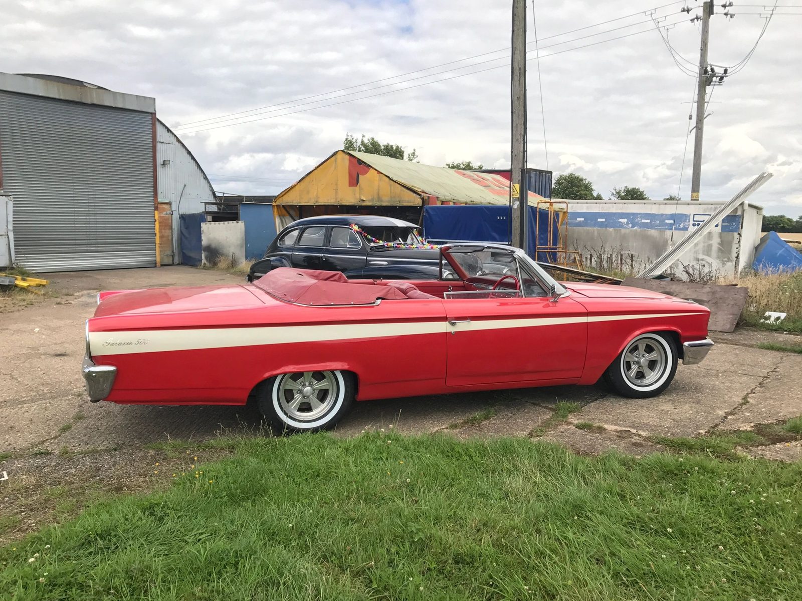 Red and cream 1963 Ford Galaxie convertible with its roof down, parked on a yard