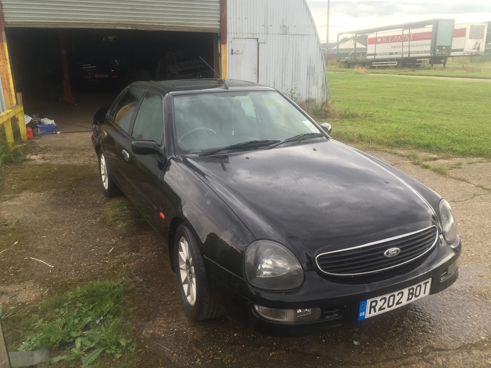 Black Ford Granada Scorpio outside a workshop, seen from the front three-quarter