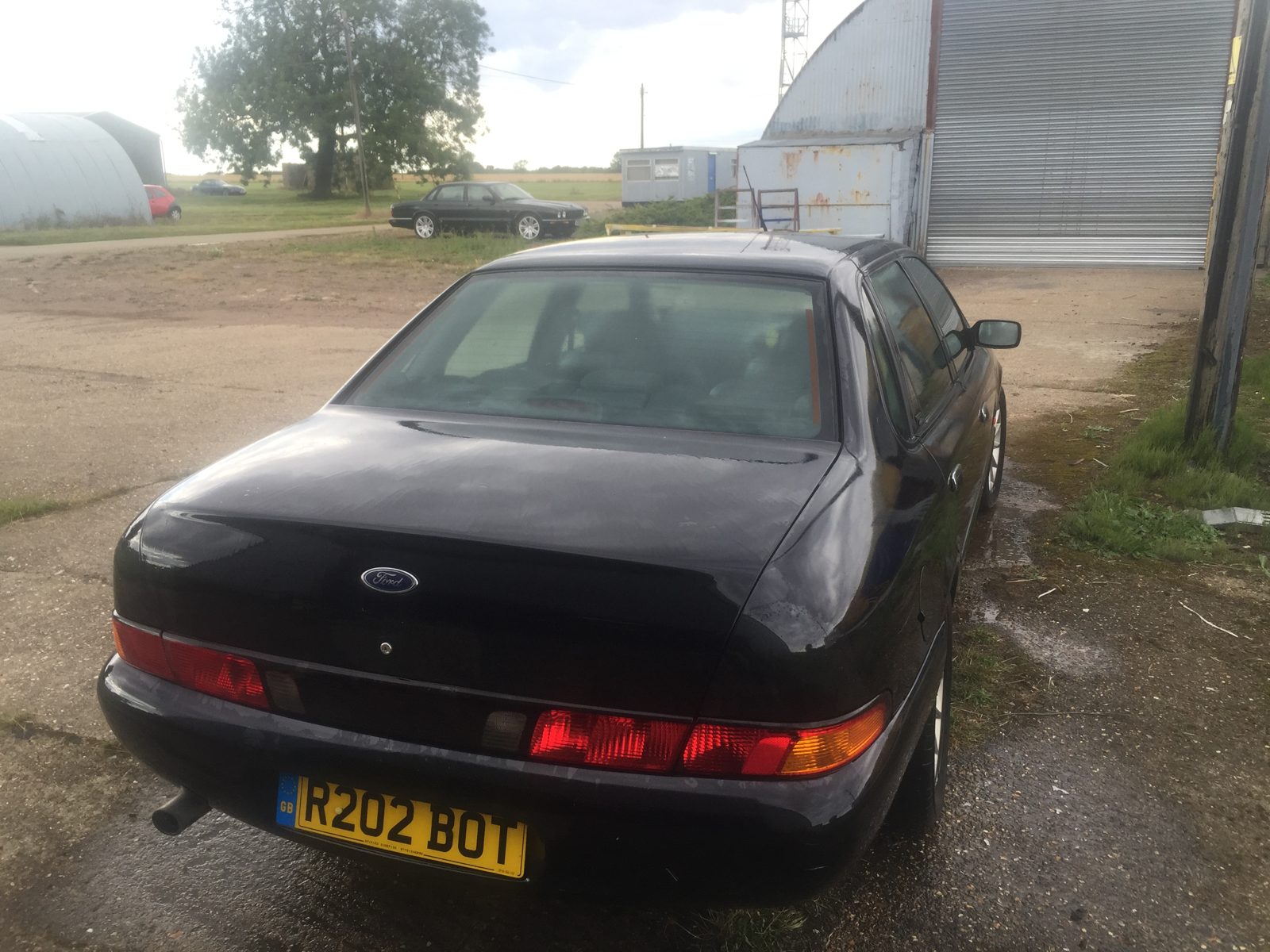 Rear three-quarter of the black Granada Scorpio on a gravel drive