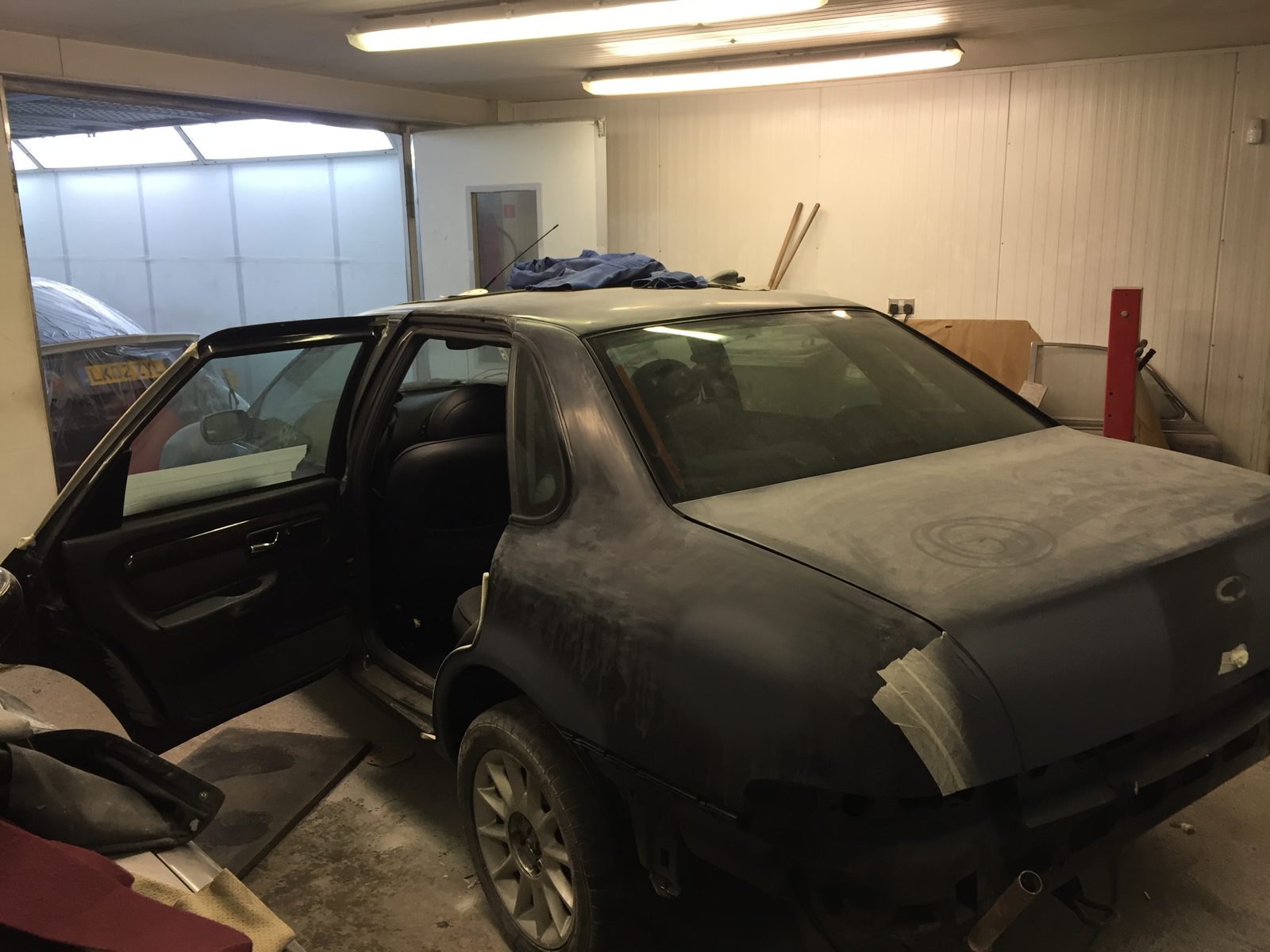 The shell in primer with a door open and the glass masked