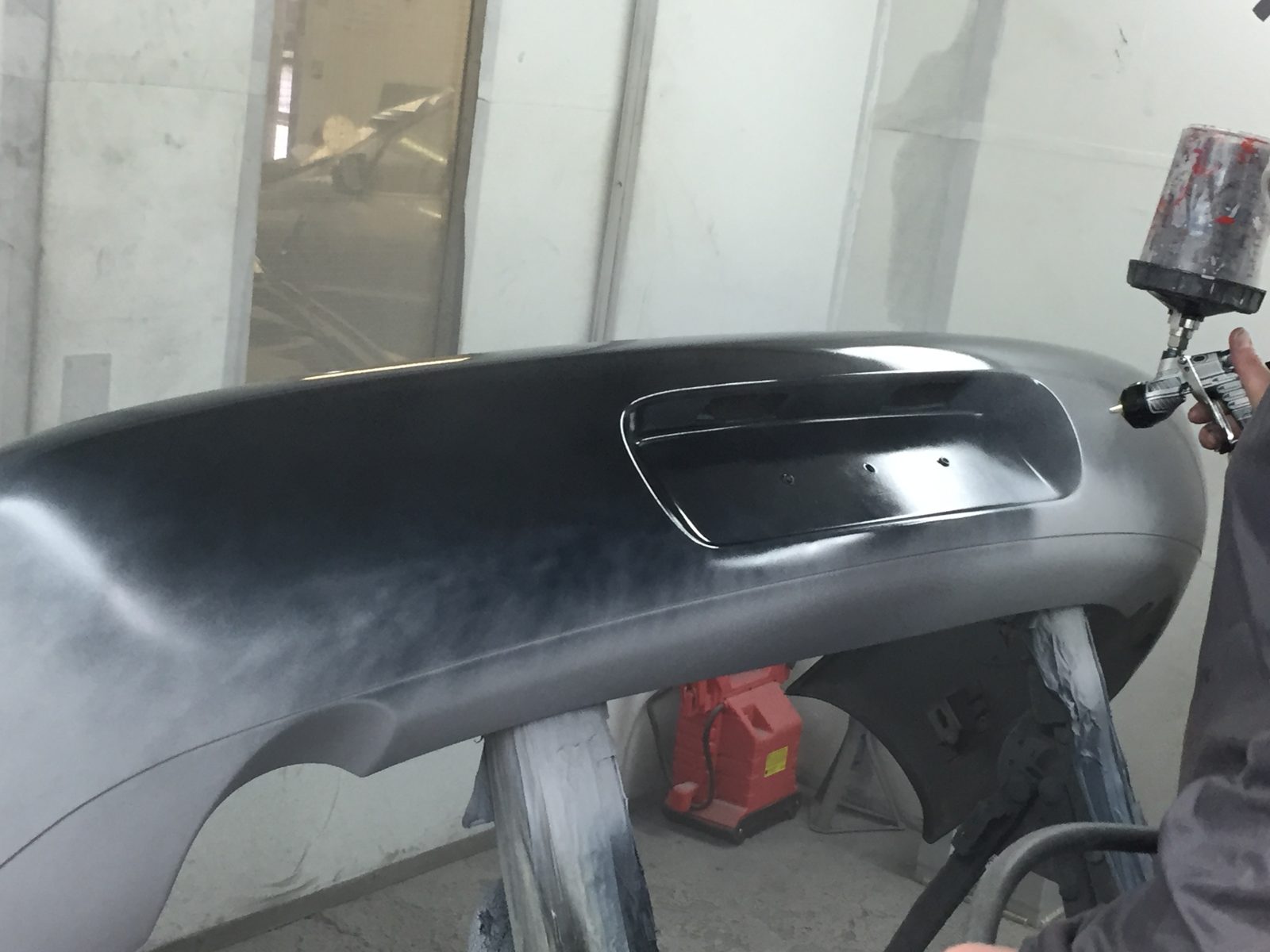 Spraying the front bumper black in the booth