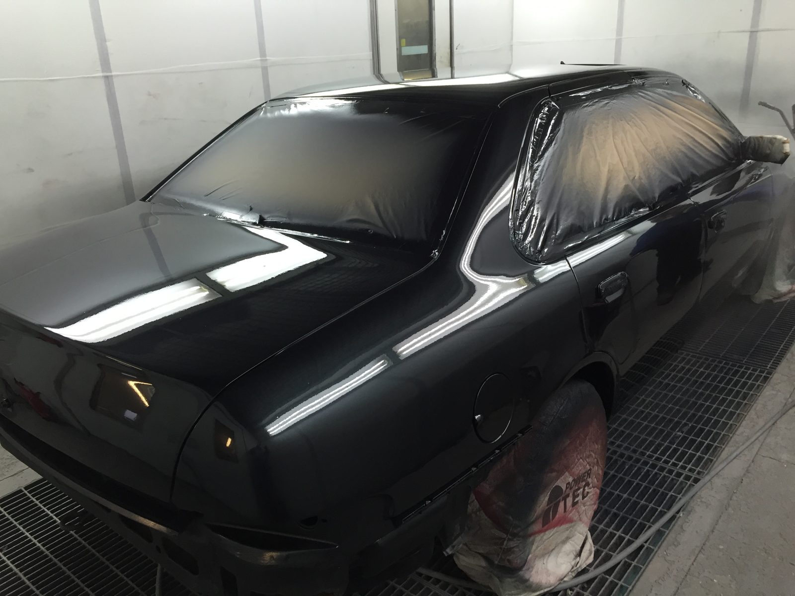 The side in fresh black paint, still masked in the booth