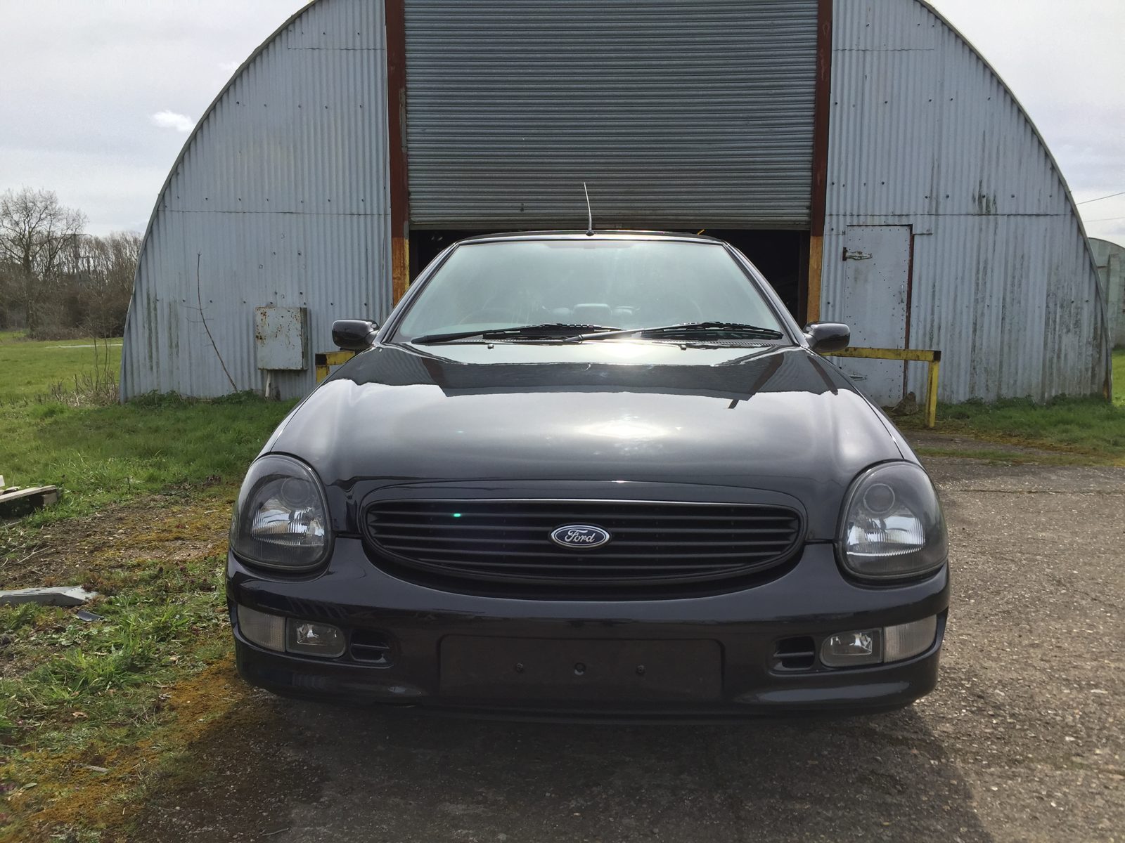 Head-on view of the black Granada Scorpio in front of the workshop
